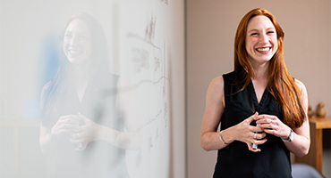 Teacher standing at whiteboard smiling