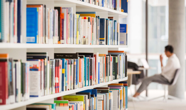 Book shelf and student seated at desk in distance